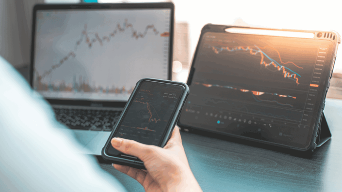 Smartphone displaying a stock market app with fluctuating graphs, highlighting stock market volatility.
